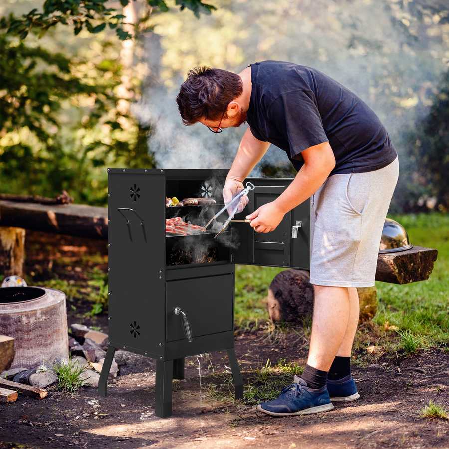 Person grilling outdoors using a portable barbecue grill in a natural setting.