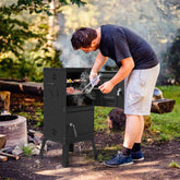 Person grilling outdoors using a portable barbecue grill in a natural setting.