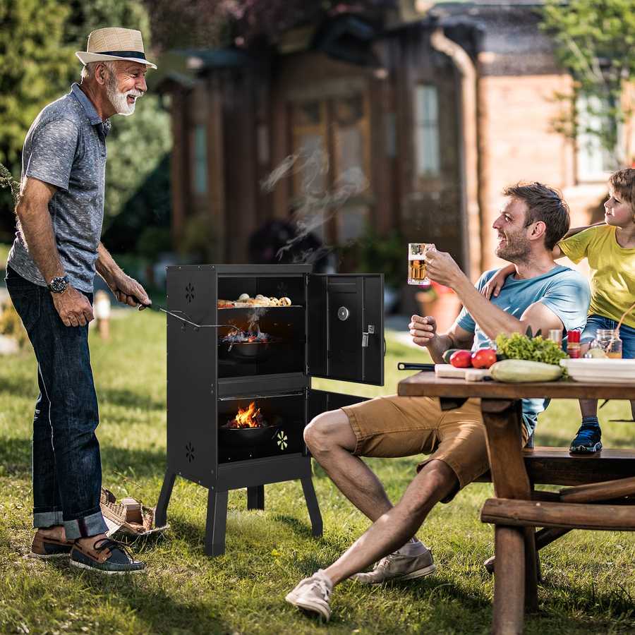 Family enjoying a barbecue outdoors with a man grilling and others sitting at a table.