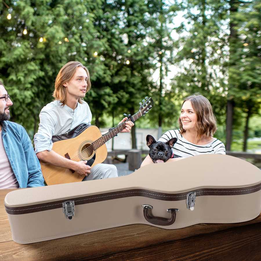 Man playing guitar with a woman and dog in an outdoor setting, with a guitar case in the foreground.