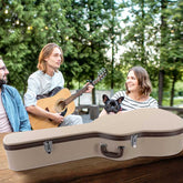 Man playing guitar with a woman and dog in an outdoor setting, with a guitar case in the foreground.