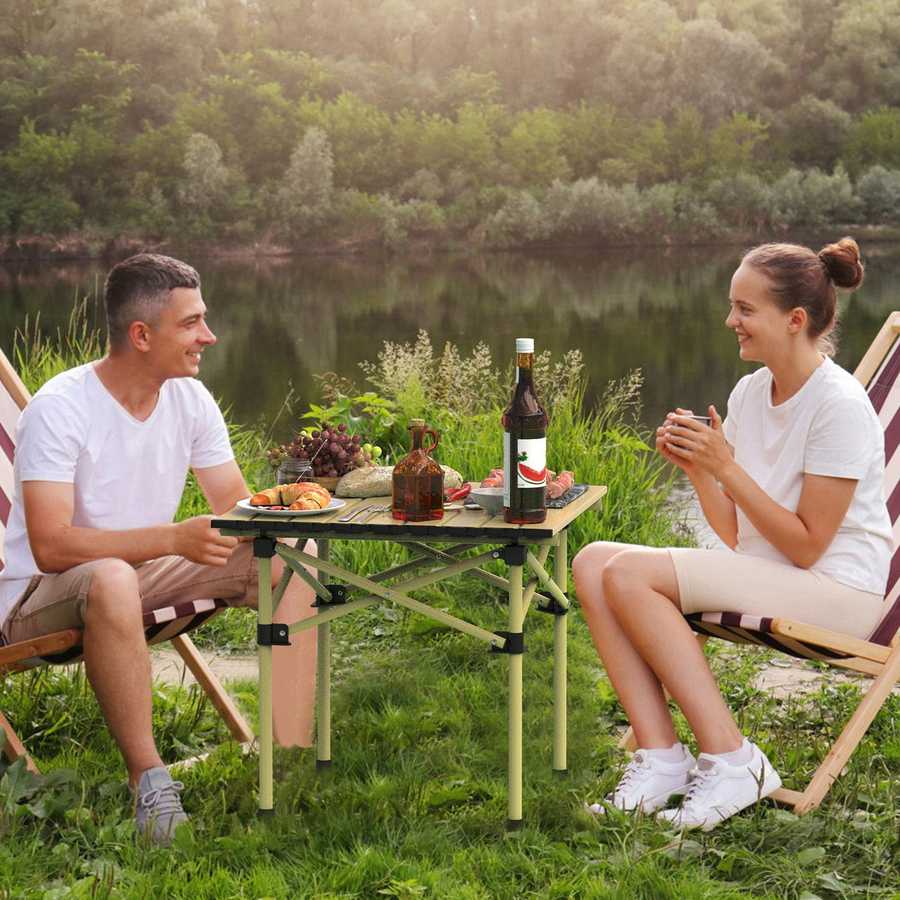 Two people sitting at a small table by a lake, enjoying a picnic.