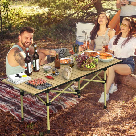 Group of people enjoying a picnic outdoors with a wooden folding table.