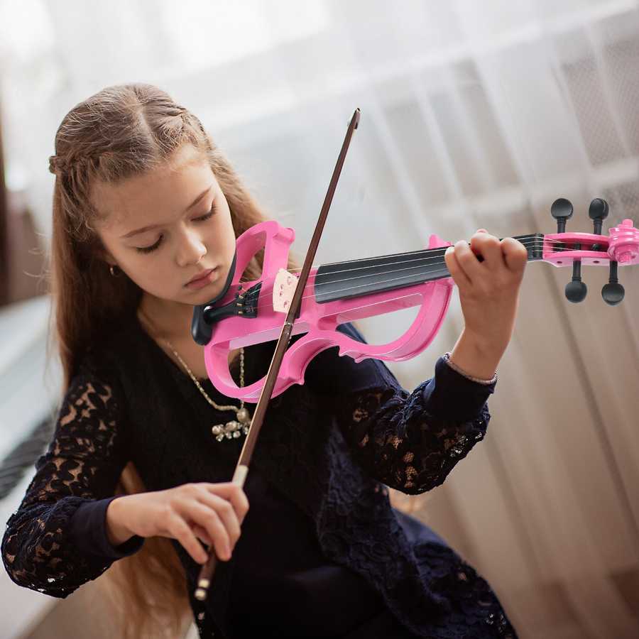 Young girl playing a pink violin with a blurred background