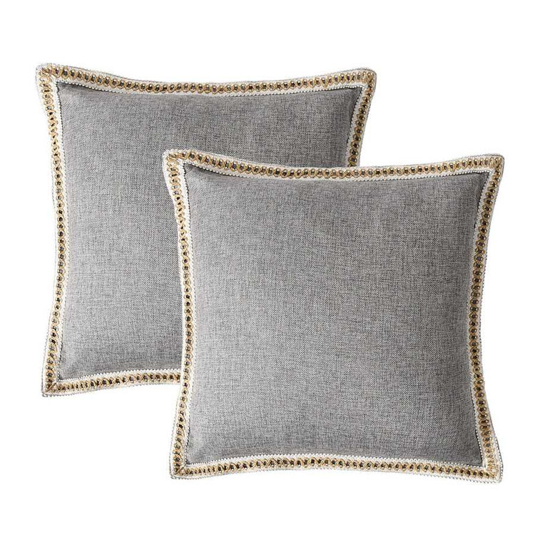 Two gray pillows with decorative trim on a white background