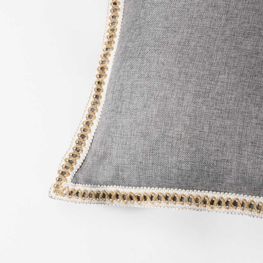 Gray pillow with decorative trim on a white background