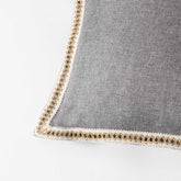 Gray pillow with decorative trim on a white background