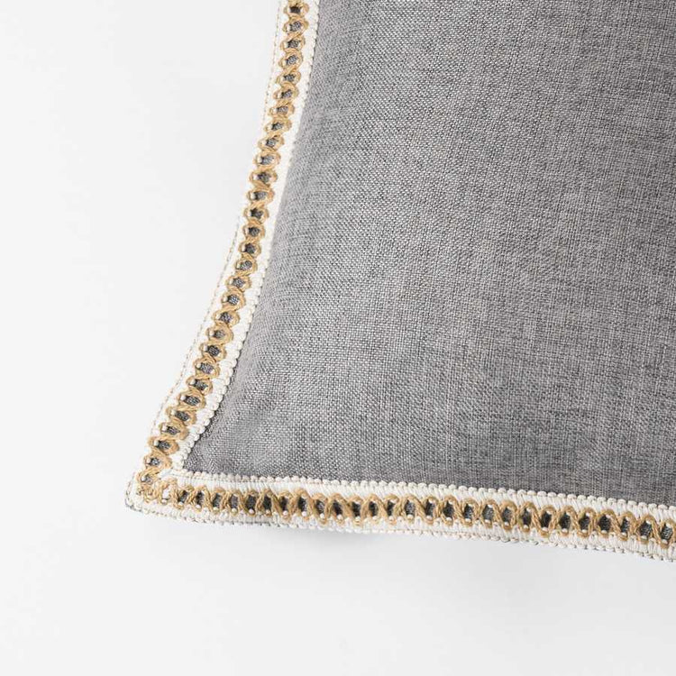 Gray pillow with decorative trim on a white background