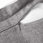 Close-up of a zipper on a textured gray fabric bag.