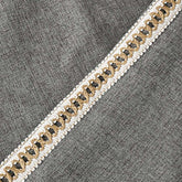 Decorative ribbon with gold and black pattern on a gray fabric background