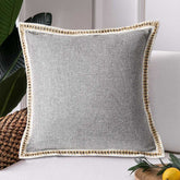Gray pillow with decorative trim on a couch