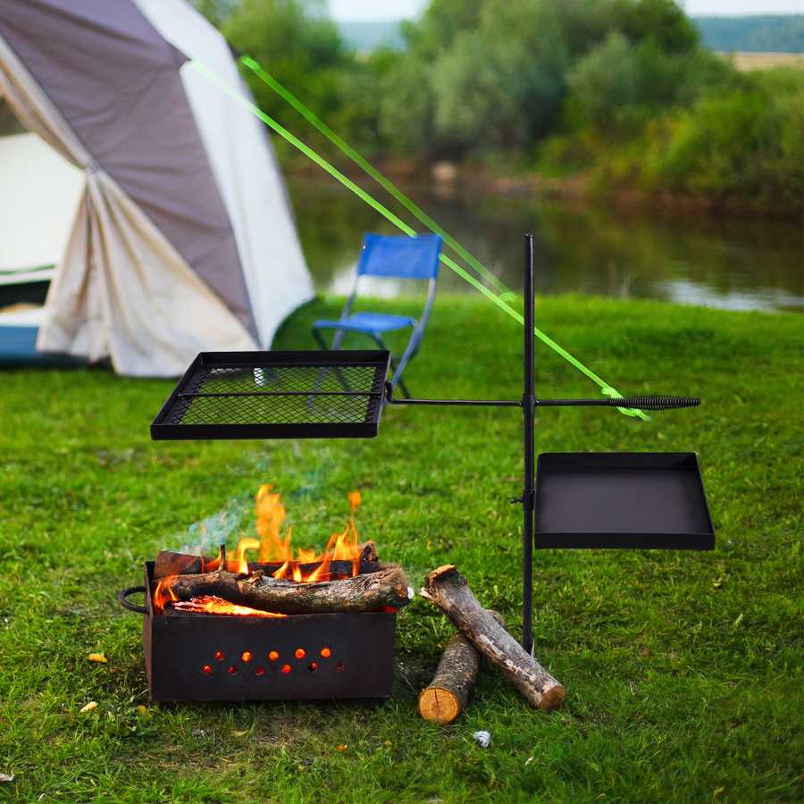 Camping scene with a grill over an open fire near a tent by a lake.