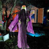 Halloween decoration of a witch with purple cape and black hat in a yard.