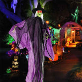 Halloween-themed decoration with a witch figure, pumpkins, and lights in a dark setting.