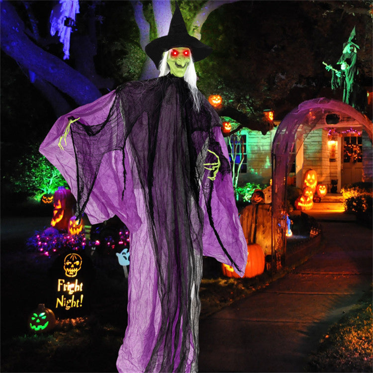 Halloween-themed decoration with a witch figure, pumpkins, and lights in a dark setting.