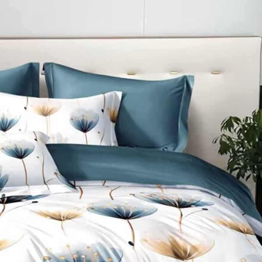 Bedding set with floral design and blue pillows on a bed.
