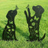 Black metal dog sculptures with butterflies and flowers on a grassy background