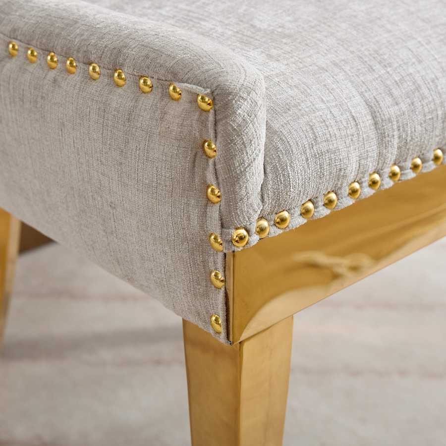 Chair with gray fabric and gold nailhead trim on a wooden frame.