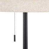 Close-up of a table lamp with a textured beige fabric shade, a black metal pole, and a black pull chain with a black toggle switch against a white background.