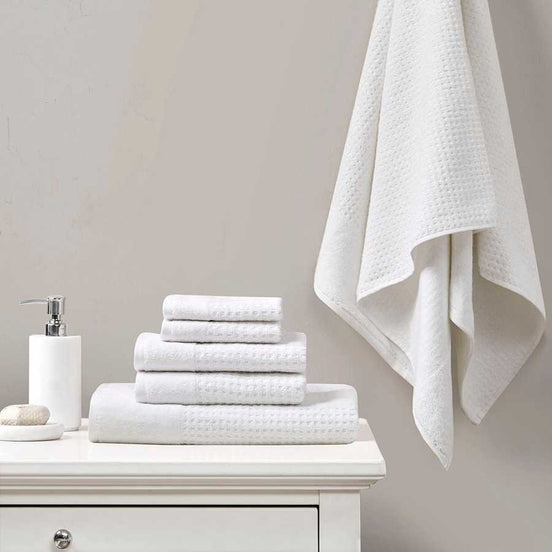 White Cotton Waffle Jacquard Bath Towel Set displayed on a vanity, featuring 6 quick drying pieces with textured design for modern bathrooms.