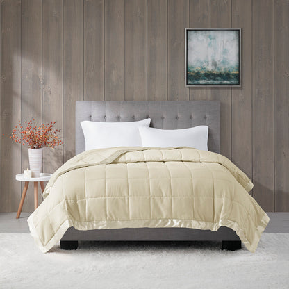 Cream Down Alternative Blanket Twin with satin trim displayed on a tufted bed, offering hypoallergenic warmth and elegant bedroom style.