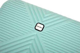 A close-up of a mint green textured suitcase or luggage piece with a central black and white Marc bane logo, set against a plain white background.