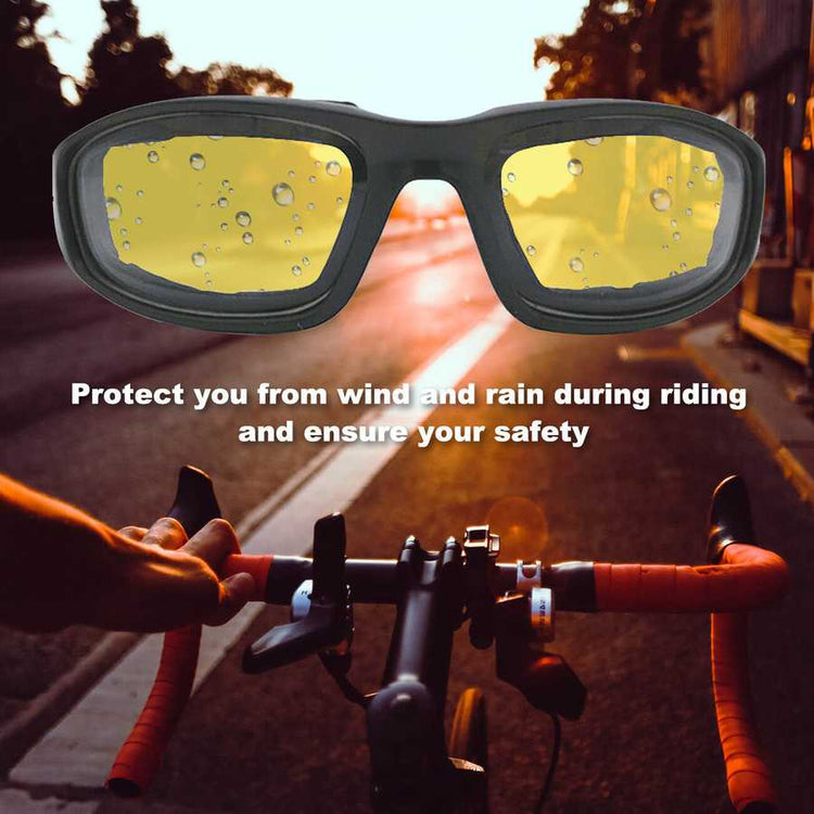 Motorcycle goggles with yellow lenses held over a motorcycle handlebar on a road.