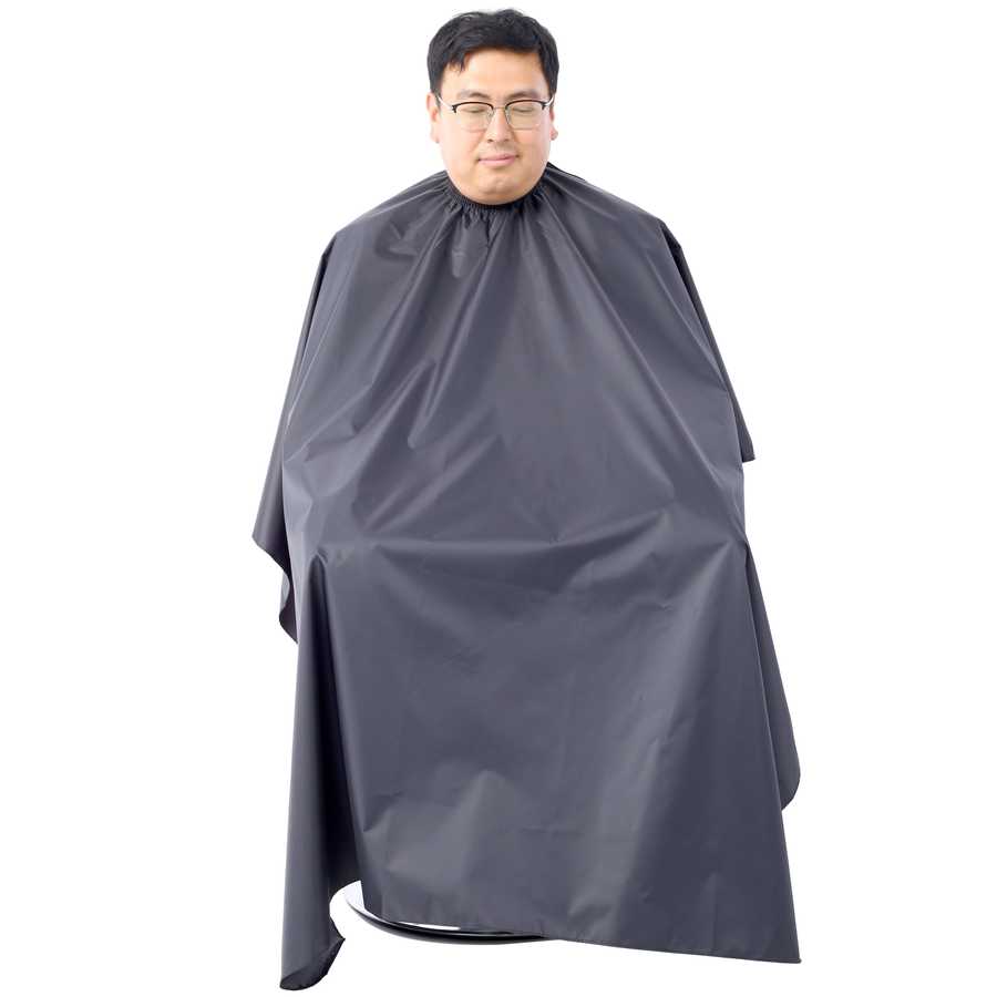 Client wearing black salon cape seated in Heavy Duty Barber Chair, showcasing full coverage and professional salon setup.