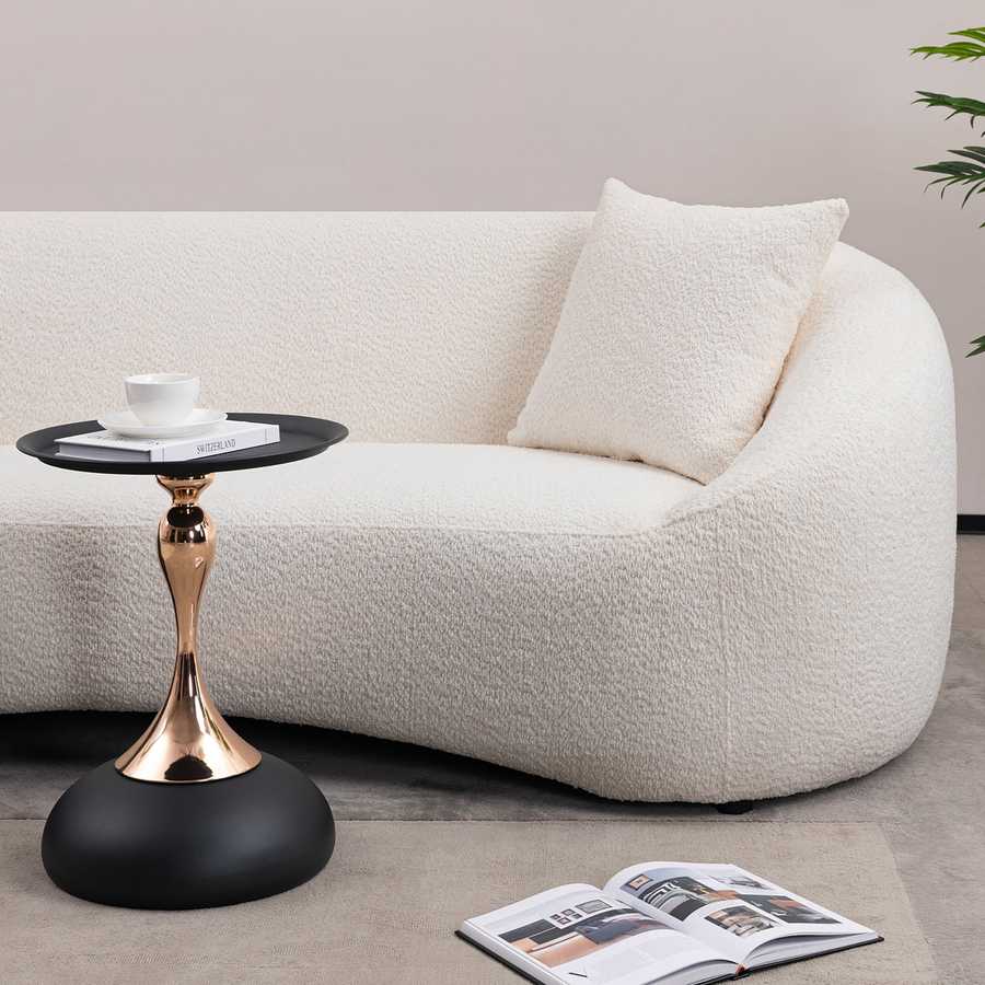 Modern Metal Mermaid Tail Coffee Table placed next to a curved white sofa, showcasing its sleek black and gold design. Functional and stylish end table.