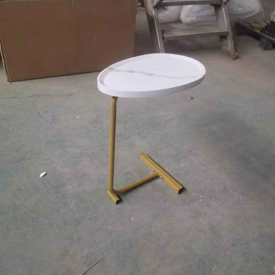 Small round table with a white top and gold base on a concrete floor.
