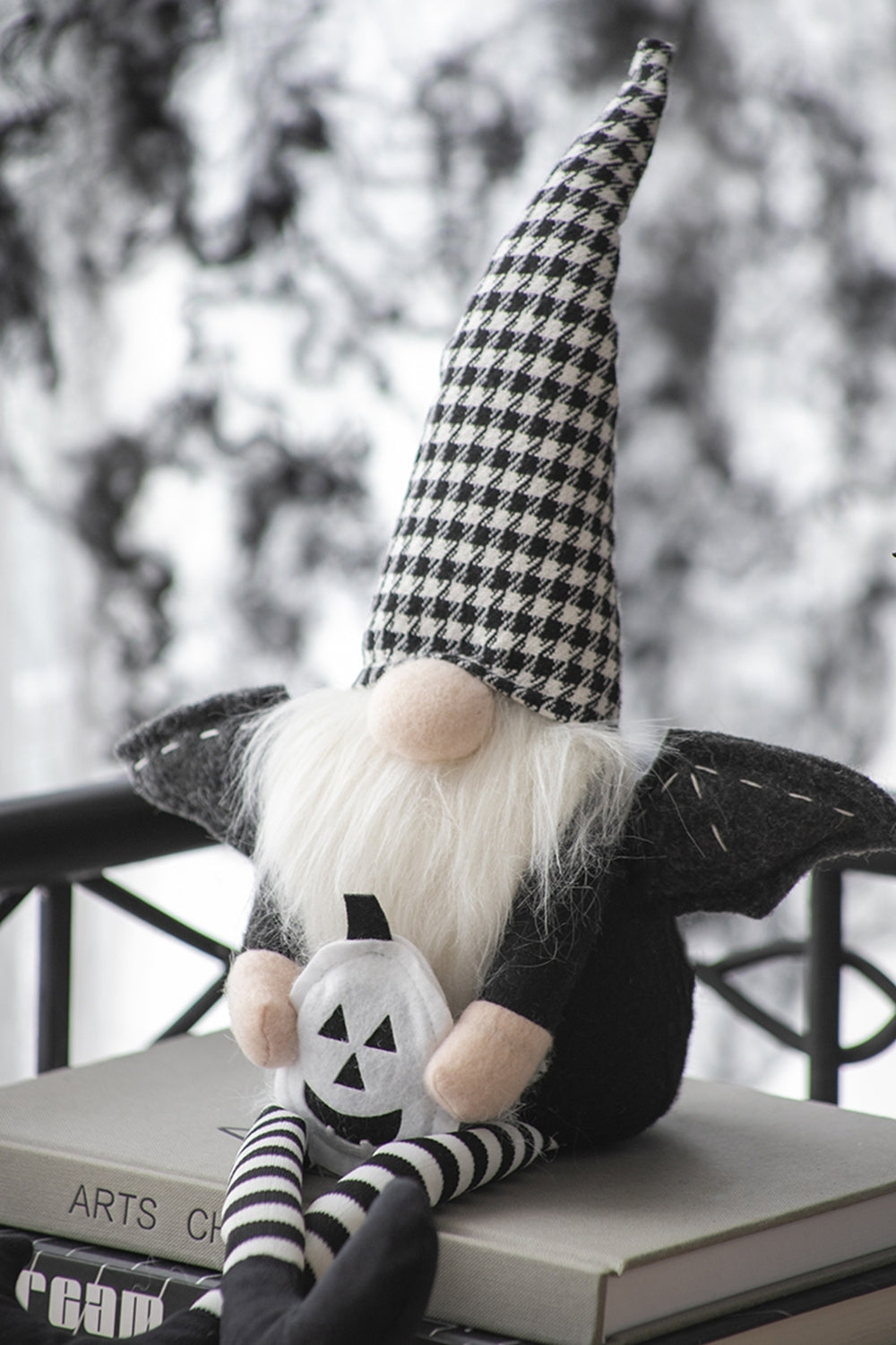 Gnome with checkered hat and pumpkin design on a surface with a blurred outdoor background