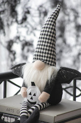 Gnome with checkered hat and pumpkin design on a surface with a blurred outdoor background