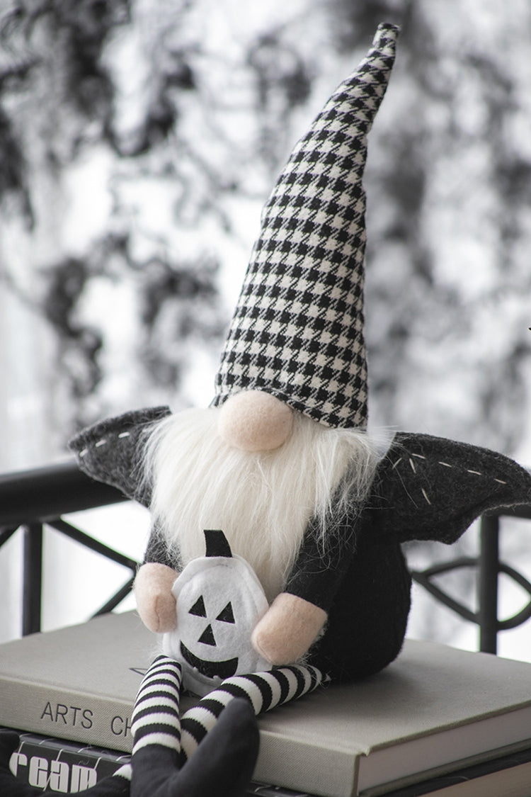Gnome with checkered hat and pumpkin design on a surface with a blurred outdoor background
