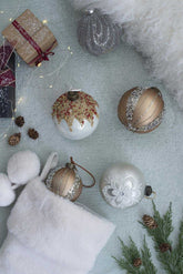 Decorative Christmas ornaments on a textured surface with a white stocking and pine cones.