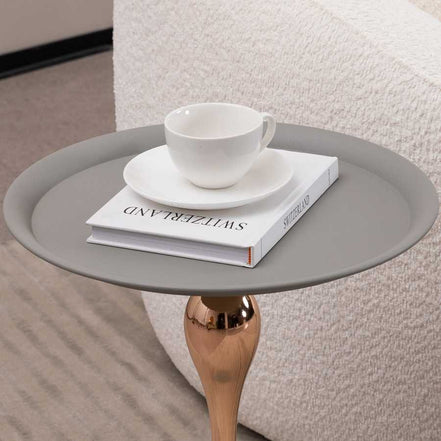 Close-up of Mermaid Tail Coffee Table top with a white cup and book, showcasing the smooth grey surface and functional design.