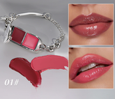 A silver-tone chain bracelet with a lipstick-shaped charm, shown alongside two close-up lip swatches and two lipstick smears. The lip swatches and shade text &