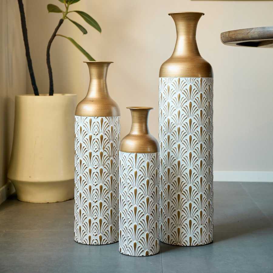 Elegant trio of metal floor vases with gold and white detailing, placed in a modern room setting for decorative impact.