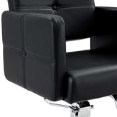 Close-up of black leather armrest with detailed stitching on salon chair