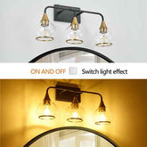 Three-light wall sconce with a matte black metal frame, clear glass shades, and brass-toned caps, shown mounted above a mirror. The top panel shows the light off, and the bottom panel shows it turned on casting a warm yellow glow.