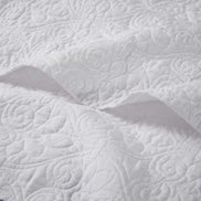 Close-up of white oversized quilted throw 60x70 showing detailed floral stitching on soft cotton fabric for elegant bedding.