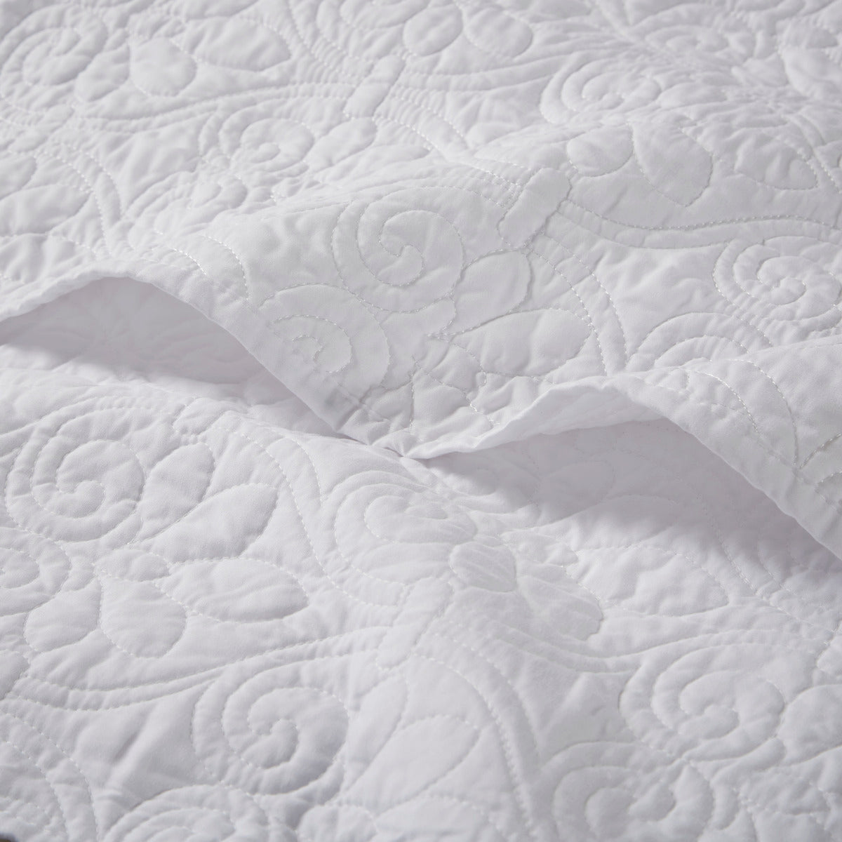 Close-up of white oversized quilted throw 60x70 showing detailed floral stitching on soft cotton fabric for elegant bedding.