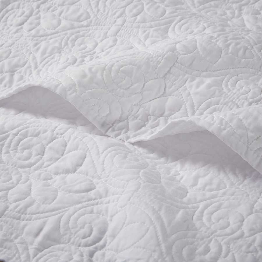Close-up of white oversized quilted throw 60x70 showing detailed floral stitching on soft cotton fabric for elegant bedding.