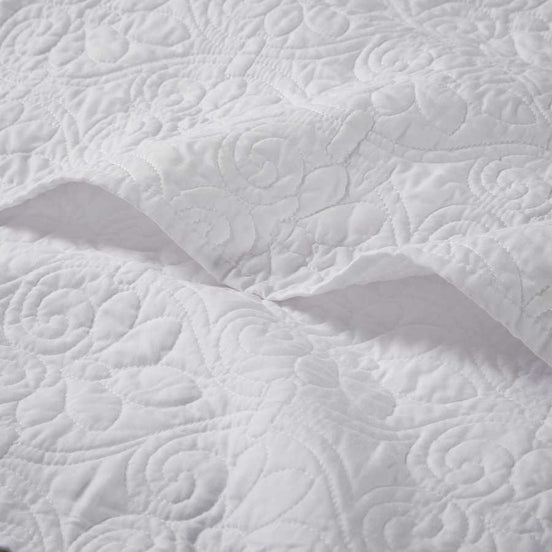 Close-up of white oversized quilted throw 60x70 showing detailed floral stitching on soft cotton fabric for elegant bedding.