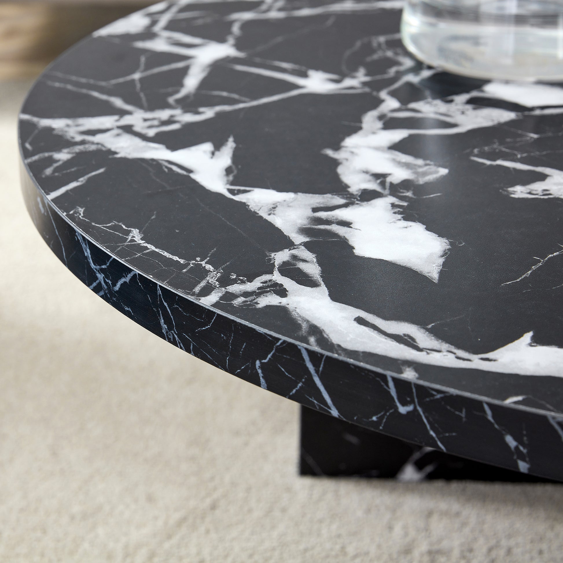 Detailed edge view of black MDF round coffee table with faux marble finish, emphasizing its smooth and durable surface.