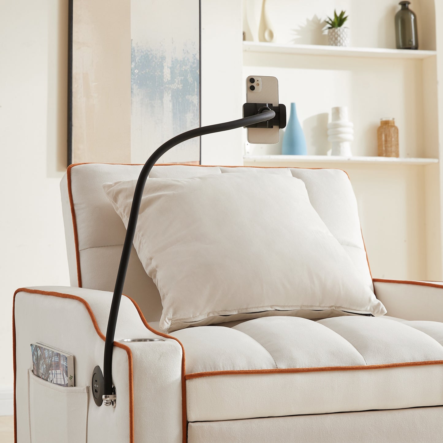 Close-up of phone holder attached to convertible beige velvet sofa bed with USB port. Perfect for hands-free device use in small spaces.