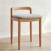 Wooden chair with a gray cushion on a light wooden floor and white wall background