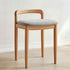 Wooden chair with a gray cushion on a light wooden floor and white wall background