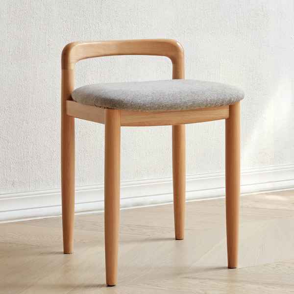 Wooden chair with a gray cushion on a light wooden floor and white wall background