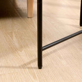 Close-up of a black metal leg on a wooden floor