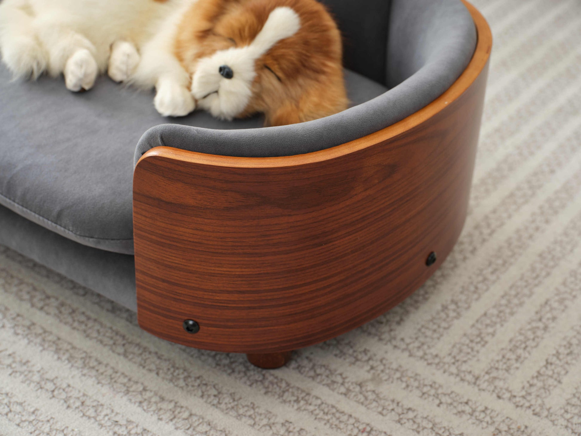 Detail of curved solid wood armrest on Scandinavian pet sofa, highlighting elegant design and velvet upholstery.